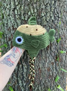 a knitted hat hanging on the side of a tree with an eyeball attached to it