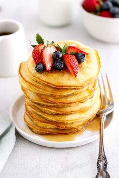 a stack of pancakes topped with berries and syrup