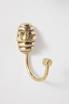 a close up of a gold hook on a white wall with a butterfly decoration hanging from it's side