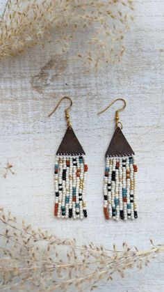 When creating these earrings I wanted to design a pattern and use a mix of colors that would enable these earrings to go with almost any outfit. These earrings are beaded by hand and the topper is made out of genuine leather. You can choose between gold, silver, and bronze hardware that is hypoallergenic.  Approx. 3 inches long Note: If you would like different colors please do not hesitate to reach out. We love custom orders and have an array of colors. Handmade Brown Heishi Beads, Brown Dangle Beaded Earrings With Tiny Beads, Unique Adjustable Beaded Earrings With Dangling Beads, Handmade White Heishi Beads Earrings, Bohemian Heishi Beaded Earrings With Dangling Beads, Bohemian Beaded Earrings With Dangling Heishi Beads, Unique Tiny Beaded Earrings For Festival, Unique Festival Earrings With Tiny Beads, Artisan Beaded Heishi Beads Earrings