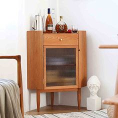 a wooden cabinet sitting on top of a rug next to a white vase and chair