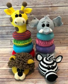 three crocheted stuffed animals sitting next to each other on a wooden surface with wood planks