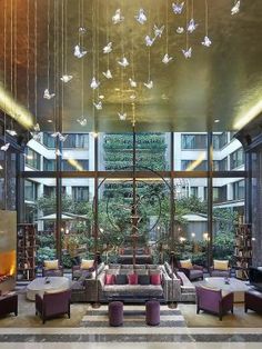 a lobby with lots of furniture and hanging butterflies on the ceiling above it, along with large windows that allow natural light into the room