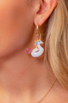 a close up of a woman's ear wearing earrings with an unicorn on it