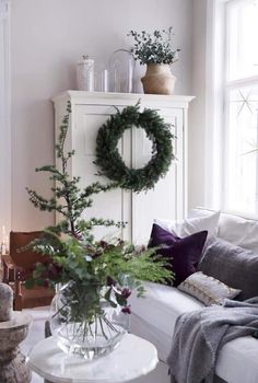 a living room filled with furniture and a wreath on top of a cabinet next to a window