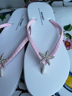 These beautiful flip flops are wrapped in matte light pink ribbon, and adorned with a silver rhinestones starfish button. Ribbon color is pink if you are needing other colors of ribbon or decoration please contact me and will be happy to accommodate you! Please choose from starfish or flower. All flip flops are handmade to order and the production time 1 to 2 weeks and then please allow additional time for shipping. Amazing for beach, weddings, flower girl or a fancy event, you choose! Please choose your size from the drop box. Adjustable Pink Flip Flops For Beach, Silver Flip Flops For The Beach, Silver Open Toe Flip Flops For Beach, Adjustable Pink Sandals For Wedding, Elegant Pink Summer Flip Flops, White Flip Flops For Beach Season Parties, Adjustable Silver Flip Flops, Adjustable Silver Open Toe Flip Flops, Silver Toe Post Flip Flops For Party