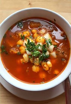 a white bowl filled with soup on top of a wooden table