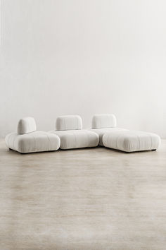 a large white couch sitting on top of a wooden floor next to a chair and ottoman