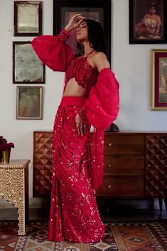 Step into iconic glamour where elegance is draped in the shimmer of scarlet palette for the season’s soirees. Our new-age concept of pre-draped saree features a chic halter neck blouse adorned with nalki crystals embellishment paired up with a sequined pre-draped skirt. Adding a hint of drama the handmade puffer sleeves complete the whole iconic look. • Pre-draped sequined skirt.• Halter-neck blouse adorned with nalki crystals and moti embellishments. • Metal hook at the back side of the blouse to conceal. • Puffed sleeves with an attached sequined dupatta.• Metal zip on the backside of the skirt along with a hook for support.From Moledro’s Fitoor collection. DELIVERY TIMEPlease allow 8-12 weeks for your outfit to arrive. FABRIC DETAILSBlouse: Butterfly Net Skirt: GeorgetteSleeves: Net Pro Floor-length Saree For Gala, Festive Floor-length Pre-draped Saree For Gala, Party Wear Draped Choli With Unstitched Blouse, Party Wear Pre-draped Saree For Gala, Floor-length, Party Choli With Unstitched Draped Blouse, Party Draped Choli With Unstitched Blouse, Floor-length Pre-draped Saree For Gala, Festive Saree For Gala, Party Pre-draped Georgette Saree