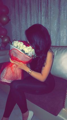 a woman sitting on a couch holding a bouquet of flowers