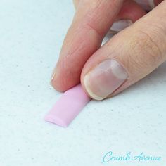 a woman's hand with pink nail polish on top of a sheet of paper