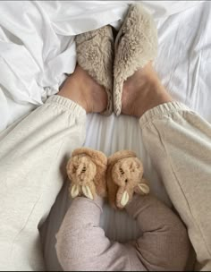 someone is laying in bed with their feet propped up on the pillow and wearing slippers