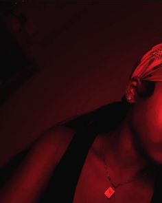 a woman with a bandana on her head is staring at the camera in red light