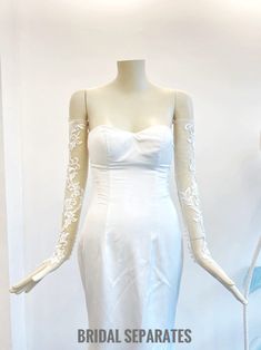 a white wedding dress on display in a room with mannequins behind it