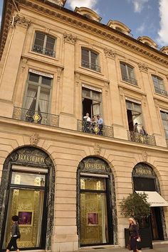 people are standing on the balconies of an old building with gold doors and windows