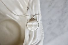 A gorgeous full moon open eye face necklace, so dainty and refined. Every moon cabochon (20mm) is hand-carved, so every little man in the moon will look slightly different. Set in a sterling silver setting and suspended from delicate sterling silver chain. Each cabochon is carved in Bali by the best Balinese master craftsmen and has extremely fine detail. Wonderful bohemian, effortlessly chic.  Wear it on its own or layer it with other necklaces. Model wears a 22" length. Made using the highest Dainty White Moon-shaped Jewelry, Dainty White Moon Phase Jewelry, Minimalist White Moon-shaped Jewelry, Minimalist White Moon Shaped Jewelry, White Round Pendant Necklace With Moon Phase, Handmade White Celestial Jewelry, White Carved Spiritual Jewelry, White Sterling Silver Moon Phase Jewelry, Handmade White Moon-shaped Necklace