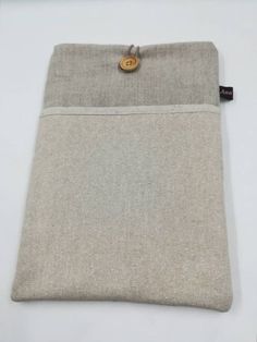 a small pouch with a button on the front and side of it, sitting on a white surface