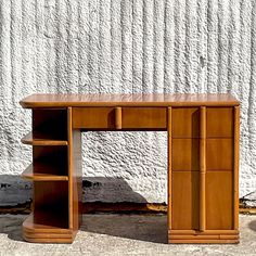 a wooden desk sitting on top of a sidewalk next to a white wall and cement floor