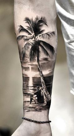 a man's arm with a palm tree on the beach and a boat in the water