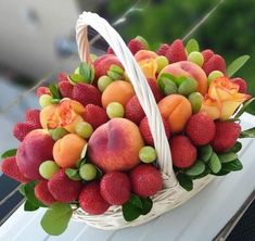 a basket filled with lots of fruit sitting on top of a window sill next to flowers