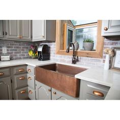 a kitchen sink sitting under a window next to a counter