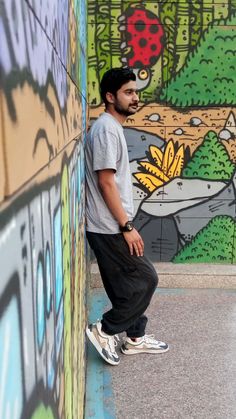 a man leaning against a wall with graffiti on it