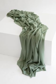 a green scarf is laying on top of a white box