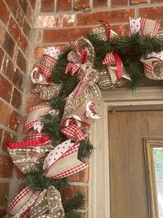 a christmas wreath is hanging on the front door with red and white ribbon around it