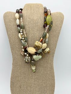 Vintage Sage Cream Heavy Art Glass Beaded Mixed Materials Multi Strand Necklace This is a heavy necklace measuring 17 1/2 inches long. This eclectic, artsy necklace is comprised of unique mixed material beads and charms including: glass beads, various stones, shell, mother of pearl, faux pearls and an a carved jade charm.  It is multicolor with the main color theme being sage green and cream.  The necklace was most likely handmade. It is in excellent vintage condition showing very little signs of wear with no damage that I can find. Please see photos for details and feel free to contact me with questions. Vintage Multi-strand Gemstone Beads Necklace, Vintage Multi-strand Gemstone Bead Necklaces, Bohemian Glass Beaded Necklace With Natural Stones, Unique Multi-strand Necklace With Variations, Bohemian Long Glass Necklace, Bohemian Multi-strand Glass Necklace, Bohemian Czech Glass Necklace With Unique Variations, Bohemian Beaded Glass Jewelry, Bohemian Double Strand Beaded Necklaces With Unique Variations