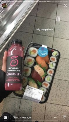 someone holding up a bottle of juice and some sushi