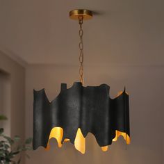 a black chandelier hanging from a ceiling in a room with a potted plant