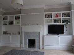 a living room with white bookcases and a fireplace