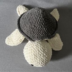 a crocheted turtle laying on top of a gray surface