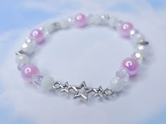 Introducing the must-have accessory of the season - a stunning elastic bracelet crafted with a combination of iridescent white acrylic beads, shimmering silver accent charms, and dainty glass beads. The centerpiece of this piece is a beautiful star charm that adds a touch of elegance and sparkle. The color scheme of white iridescent, violet, and silver gives this bracelet a unique and feminine look, perfect for any dolly, coquette, or angel core style. With its elastic design, this bracelet is e White Star-shaped Adjustable Beaded Bracelets, Adjustable White Star-shaped Beaded Bracelets, White Star Bracelets For Party, White Star-shaped Party Bracelets, Adjustable White Charm Bracelet With Star Charm, White Stretch Bracelet With Faceted Beads For Party, Adjustable White Star Charm Bracelet, Dolly Coquette, Cute Beaded Bracelet