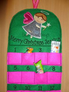 a felt christmas ornament hanging on a wooden table with candy and candies