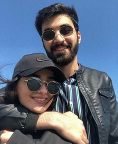 a man and woman are smiling for the camera while wearing sun glasses, hats and jackets