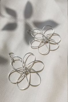 Flower power! Bold, floral wire earrings inspired by summer daisies. Stand out from the crowd with these fun statement pieces. Simple yet stunning. Lightweight, shiny, and perfect for long wear. Made by hand from your choice of silver or gold plated wire. The flower center is wrapped with either .999 fine silver wire or fine gold wire.  Ear hooks are either .925 sterling silver or gold fill, so this design may be enjoyed by sensitive ears. Earrings measure approx. 2 inches across. Drop is 1.5 in Droopy Flowers, Wire Flower Earrings, Wire Flowers, Flower Center, Floral Wire, Gold Wire, Wire Earrings, Sensitive Ears, Flower Earrings