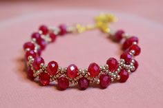 a red beaded bracelet on a pink surface