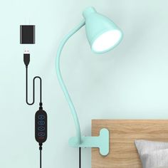 a wall mounted lamp next to a bed with a phone plugged into the headboard