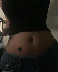 a woman's stomach with a small star tattoo on the side of her belly