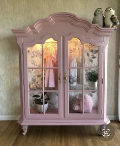 a pink china cabinet sitting on top of a hard wood floor next to a wall