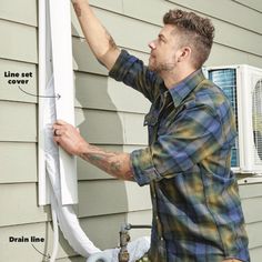 a man fixing an air conditioner on the side of a house