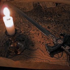 a candle is lit next to a knife on a table with an old world map