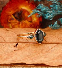 a close up of a ring on top of a leaf with flowers in the background