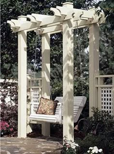 a white bench sitting under a pergolated arbor with pillows on it's back