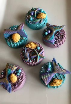 four decorated cookies sitting on top of a white plate with blue and purple icing