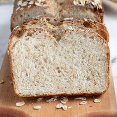 a loaf of bread sitting on top of a cutting board next to sliced oats