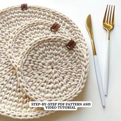 two crocheted placemats on top of each other with gold forks next to them