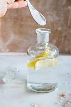 a person is spooning lemon into a glass bottle