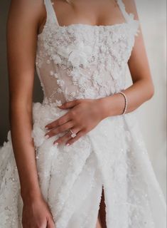 a woman in a white wedding dress holding her hand on her waist and wearing a diamond ring